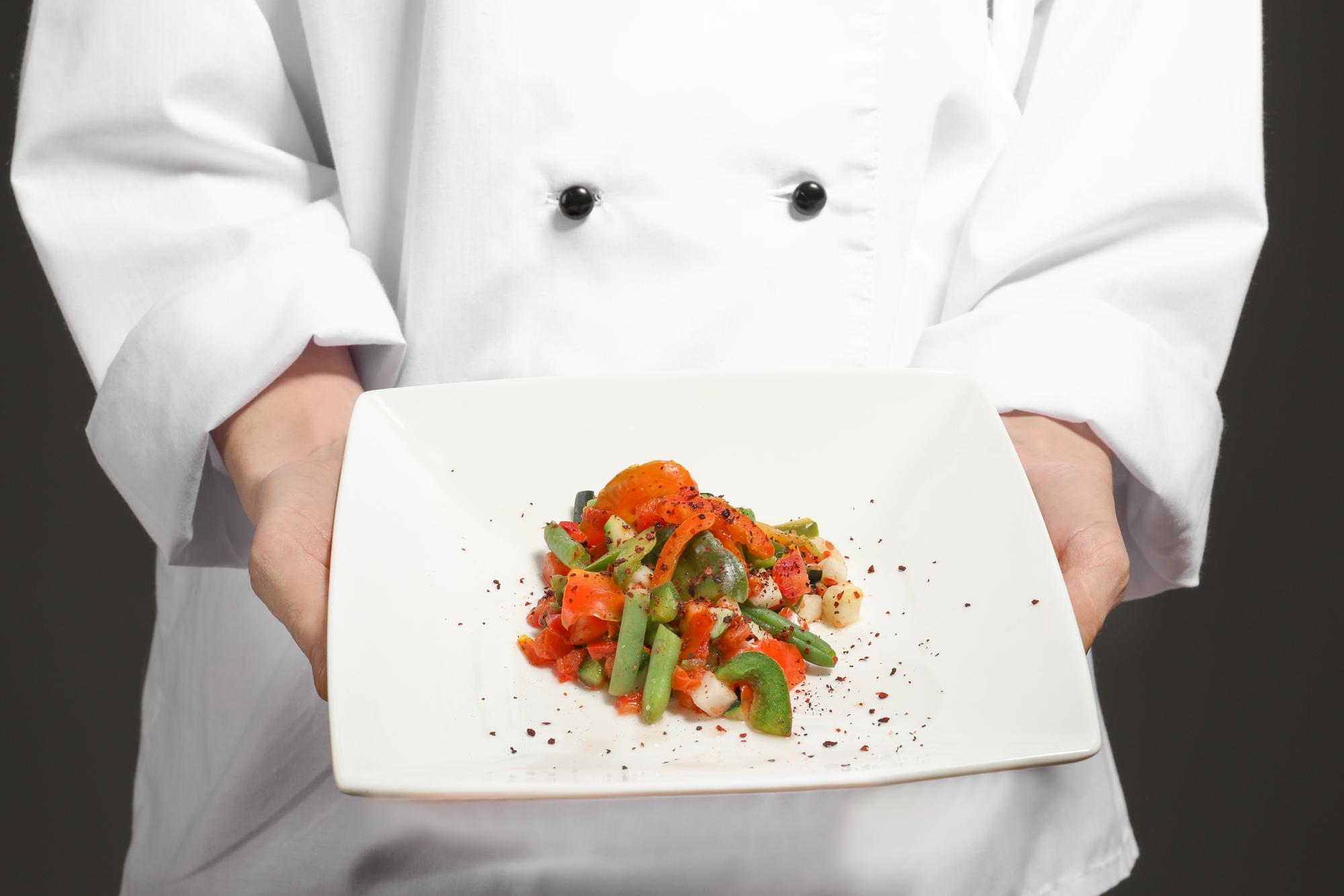 Chef moderno che prepara un piatto su banco in legno
